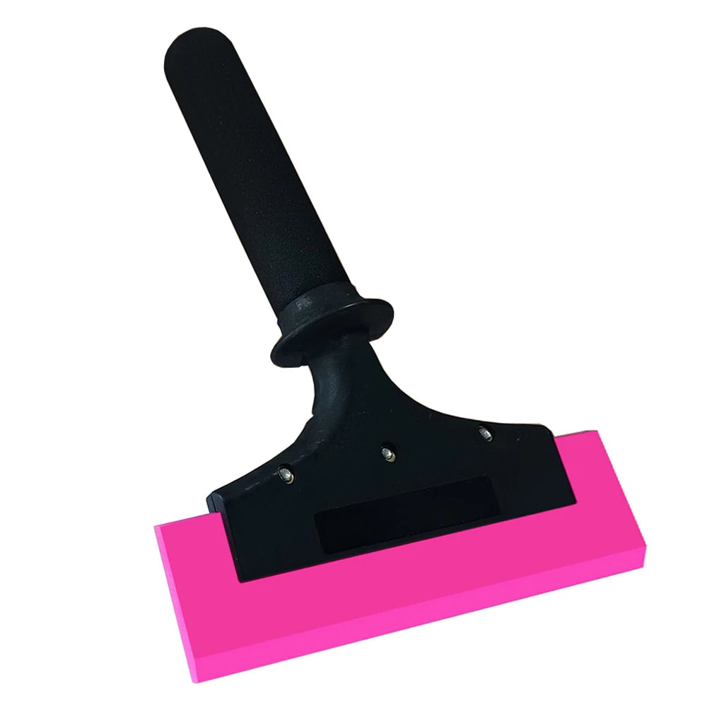 A black rubber squeegee with an anti-slip nylon handle resting on a pink surface.