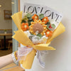 A bouquet of handmade crochet artificial flowers in orange and yellow tones wrapped in yellow paper.