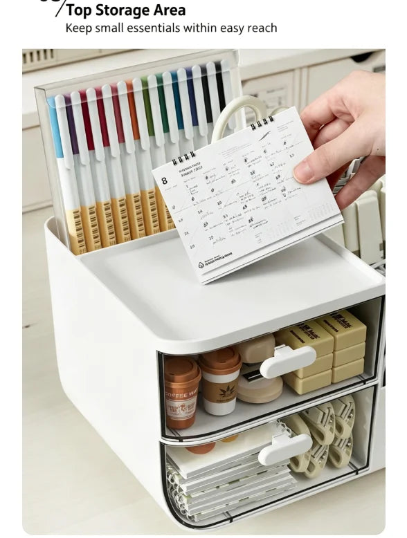 A white desk organizer with transparent drawers holds pens and a paper list.
