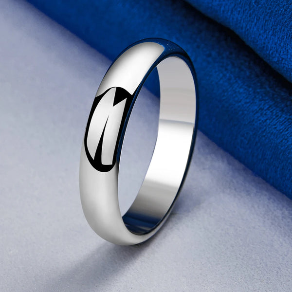 Bague en argent sterling poli avec un design géométrique noir sur fond de tissu bleu.