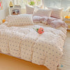 A light pink floral duvet cover set with a matching flat sheet and pillows displayed on a bed.