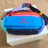 A color block waterproof nylon fanny pack featuring blue, purple, orange, and black panels resting on a white box.