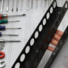 A close-up view of a black wall-mounted tool organizer holding various hand tools like pliers, screwdrivers, and wrenches.