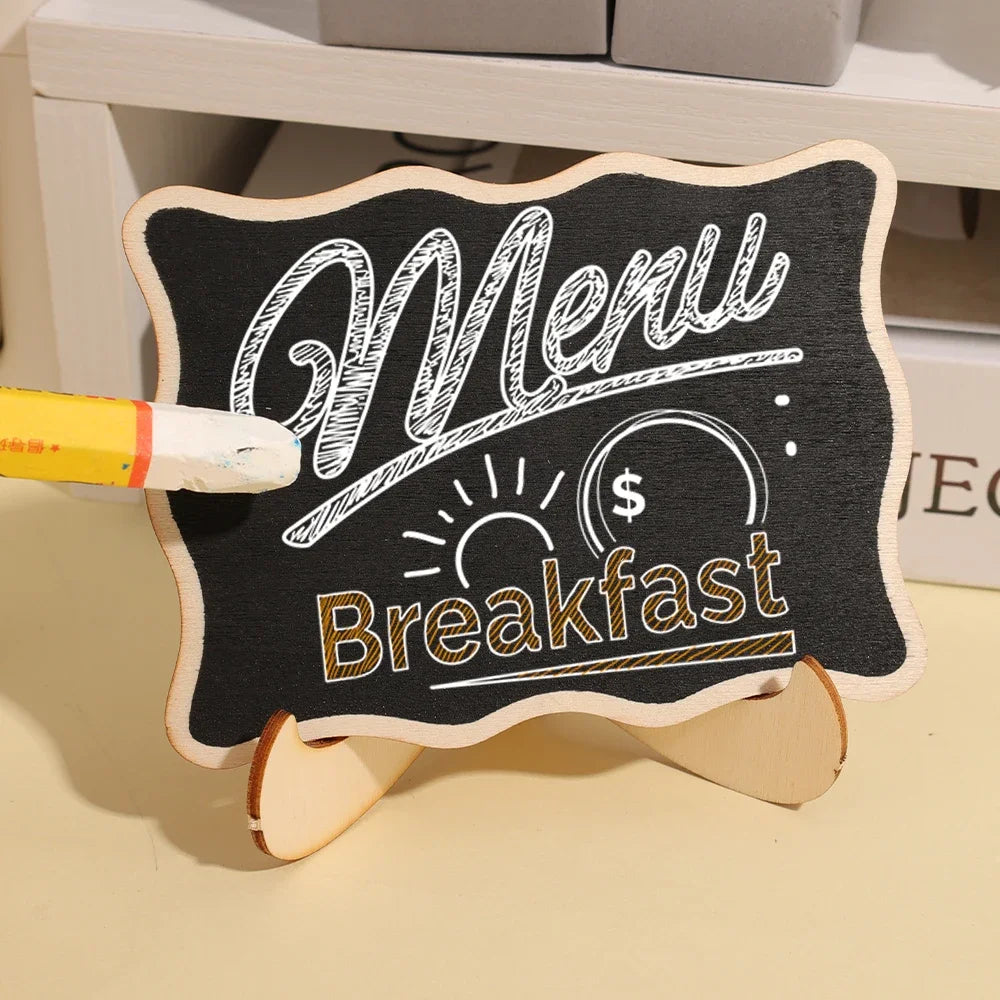 A mini wooden chalkboard sign with handwritten white text for a breakfast menu is displayed on a light surface.