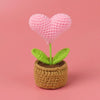 Handcrafted crochet heart flower in a woven pot with green leaves