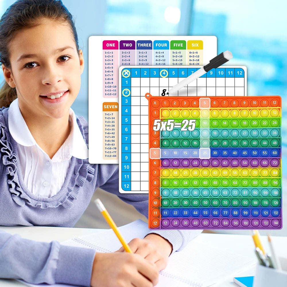 A smiling girl is writing on a sheet of paper next to a multiplication practice flashcard set and an eraser pen.