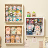 A wall-mounted display case featuring various collectible dolls and figurines in clear plastic compartments.