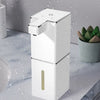 A white touchless infrared smart soap dispenser with a gold accent is shown against a background of water droplets.
