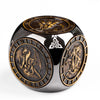 A dark metal spinner dice cube featuring intricate designs and a gold-colored top surface.