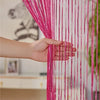 A hand is pulling a vibrant pink tassel string curtain, made of fine threads, across a doorway.