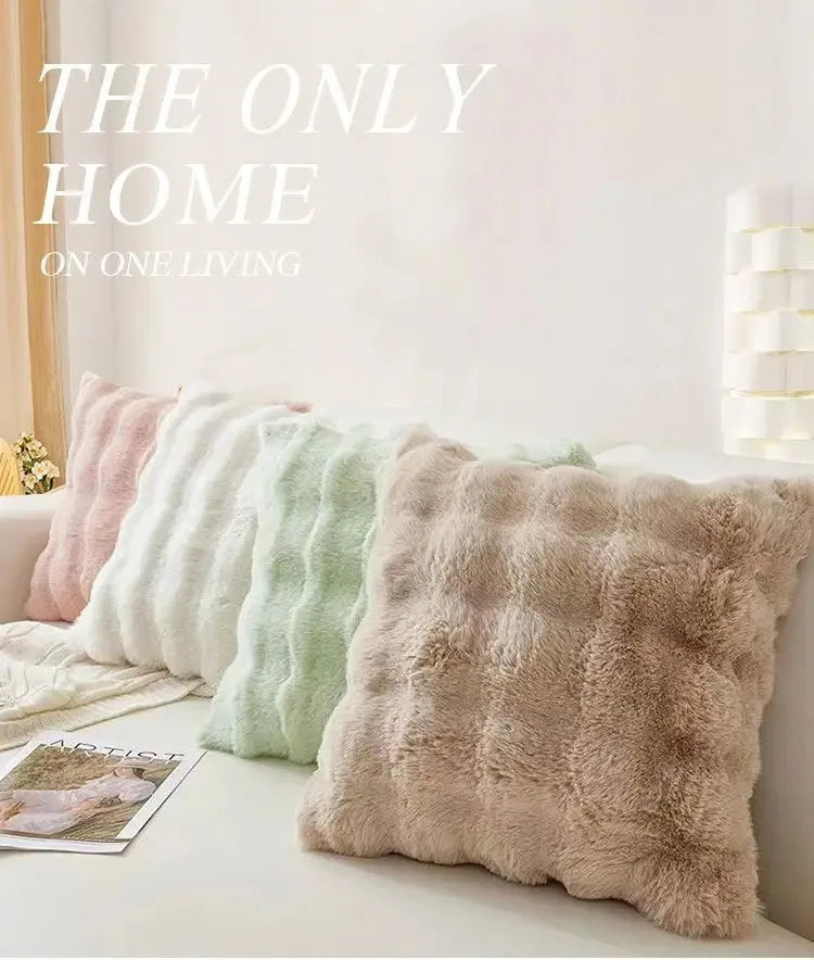 A collection of fluffy decorative pillow covers in pastel shades lined up on a white surface.