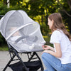 A woman is adjusting a universal baby mosquito net cover over a baby in a bassinet outdoors.