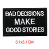 Black embroidered iron-on letter patch with white text that reads BAD DECISIONS MAKE GOOD STORIES