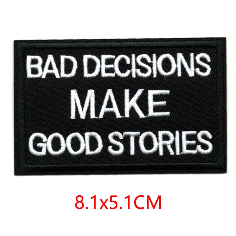 Black embroidered iron-on letter patch with white text that reads BAD DECISIONS MAKE GOOD STORIES
