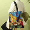 A canvas tote bag featuring a Van Gogh painting of a street scene at night, held by a person.
