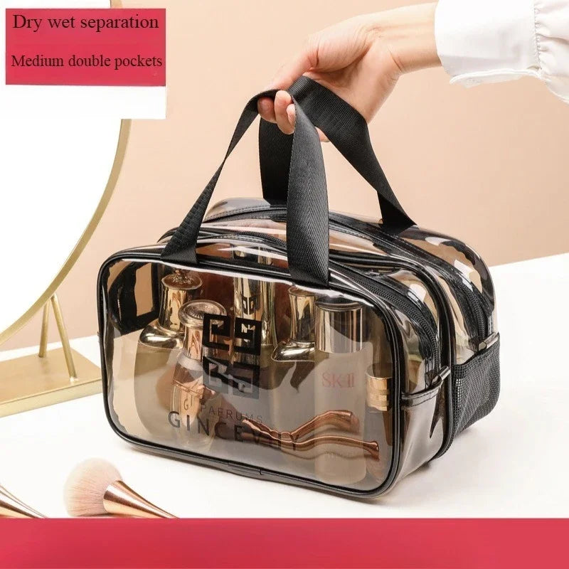 A hand is holding a clear transparent PVC travel toiletry bag with black straps and medium double pockets.