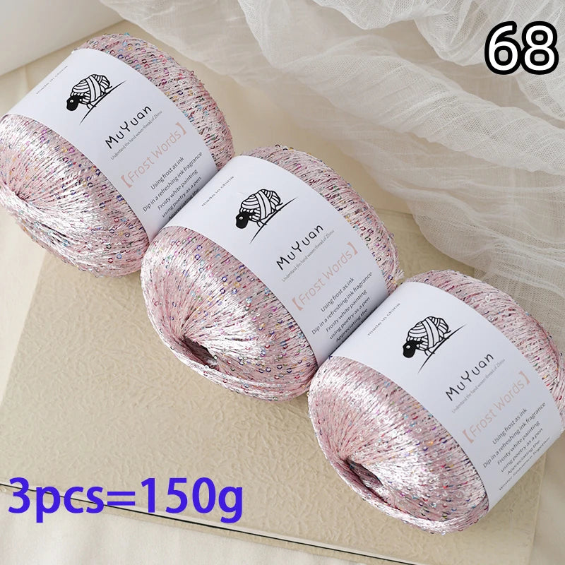 Three balls of pink glitter yarn labeled MuYuan Frost Words are displayed on a light surface.