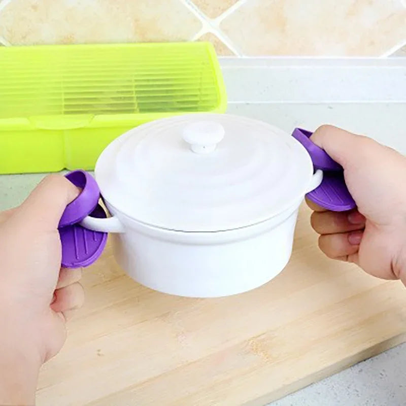 A hand is holding a white heat-resistant silicone pot with a lid, next to a bright yellow silicone item.