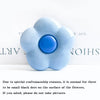 A light blue, flower-shaped foldable phone grip stand with a blue center and small black dots on the surface.