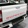 Close-up of a white Ford Super Duty truck tailgate with a red decal that reads SUPER DUTY.