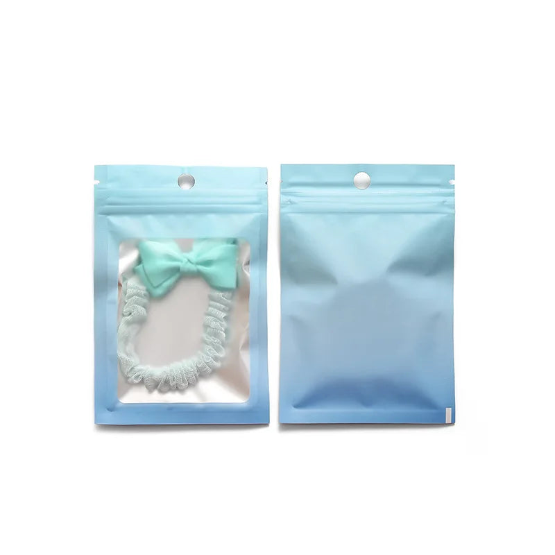 Two light blue gradient resealable zipper pouches with clear windows containing a mint green bow.