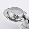 A hand holds a round stainless steel sink drain strainer with a fine mesh pattern.