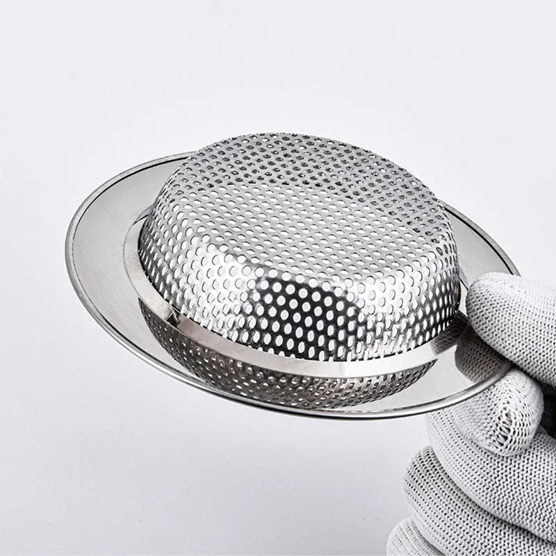 A hand holds a round stainless steel sink drain strainer with a fine mesh pattern.