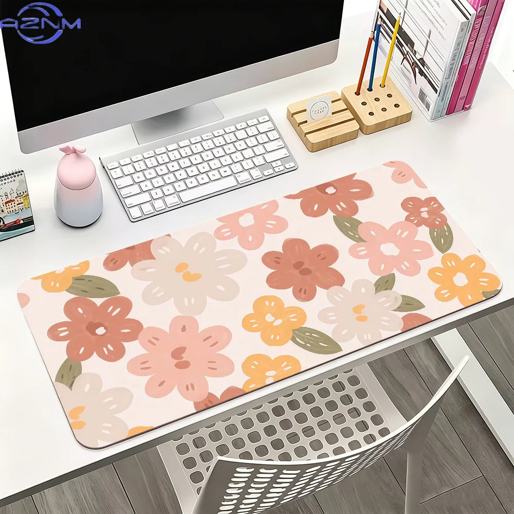 A pink floral mouse pad with various flower designs is displayed on a white desk next to a computer monitor and stationery.
