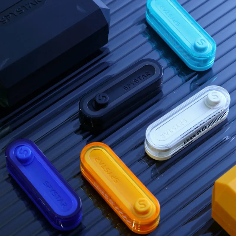 A collection of colorful metal fidget sliders in blue, cyan, black, white, and orange arranged on a dark surface.