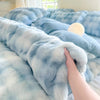 A hand is touching a light blue plush fleece duvet cover with a rabbit design on a bed.