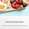 A hand is assembling a wooden jigsaw puzzle featuring large animal and traffic themed pieces.