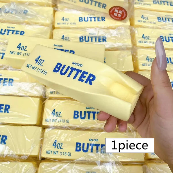 Eine Hand hält einen gelben Butterstiel-Squishy-Spielzeug in klaren Plastetüten.