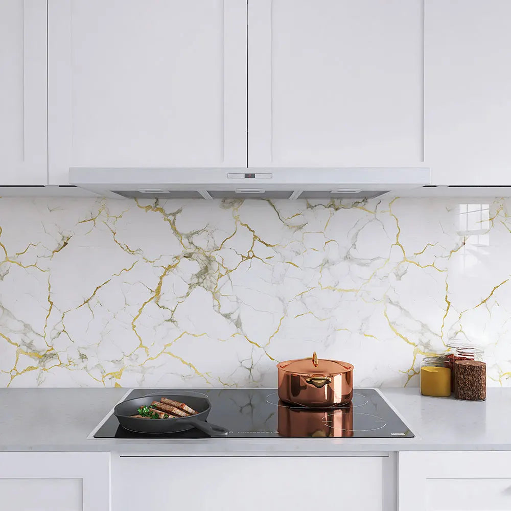 A kitchen countertop featuring white cabinets, a stainless steel hood, and a backsplash with gold marble-patterned wallpaper.