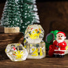 A set of clear resin dice featuring animal figures and numbers, displayed in front of a green Christmas tree.