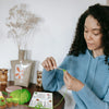 A person is holding a beginner crochet kit with green yarn and various plant and animal projects.