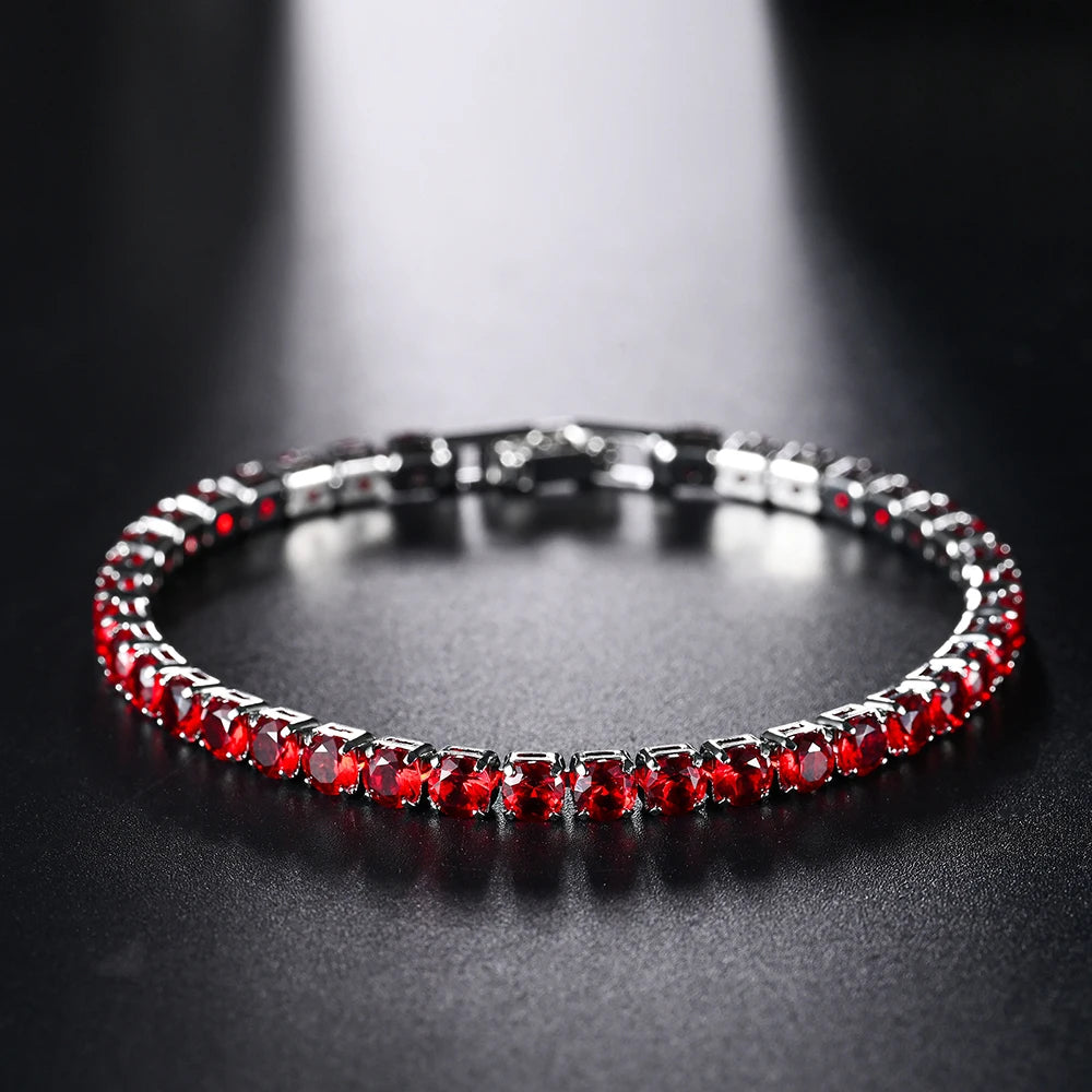 Bracelet de tennis en gemme rouge avec sertissage micro pavé sur une surface sombre.