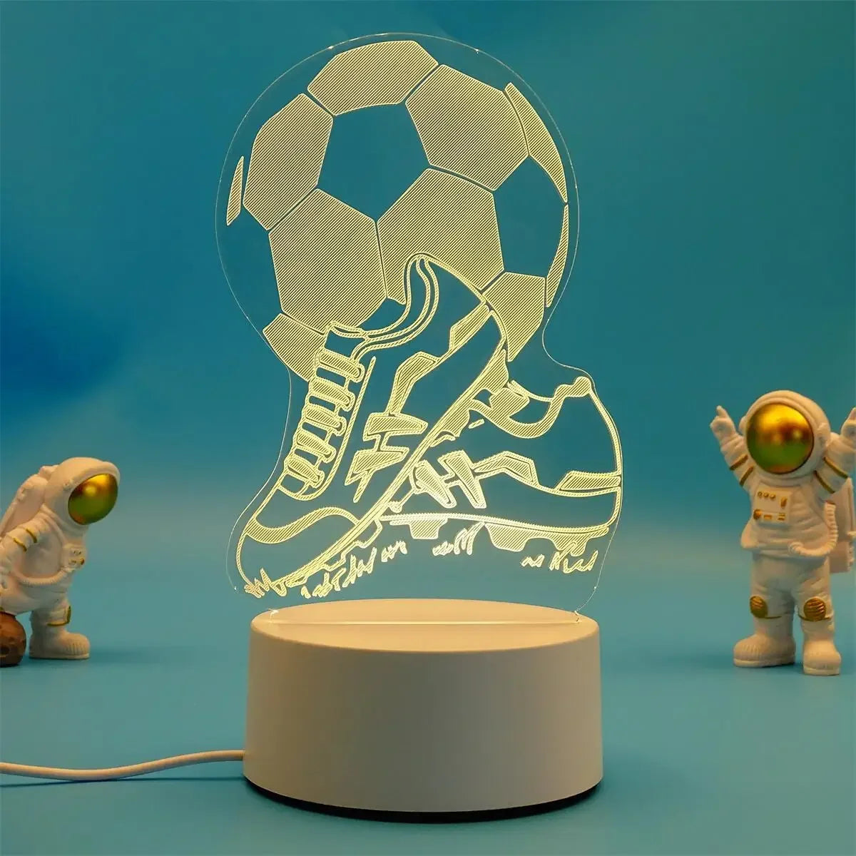 A clear acrylic night light lamp shaped like a soccer ball and a boot, illuminating the objects below.