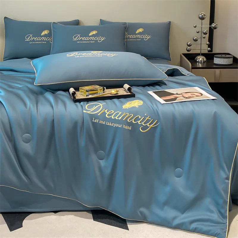 A light blue comforter and pillows featuring embroidered Dreamcity text.