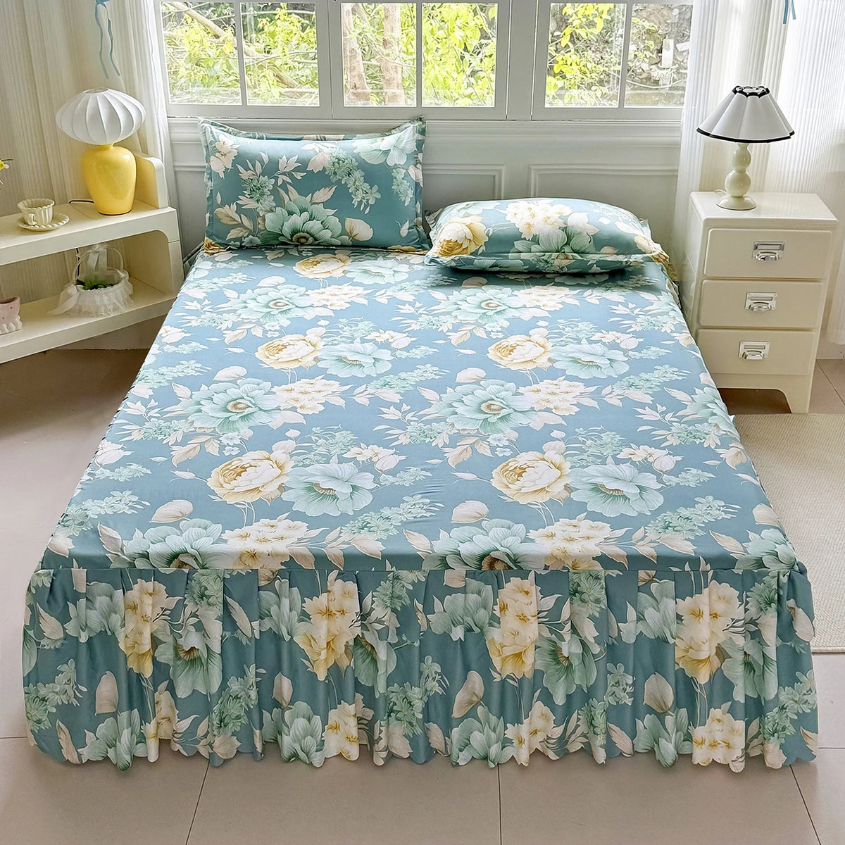 A light blue floral print bed skirt and pillowcase set with green foliage and yellow accents.
