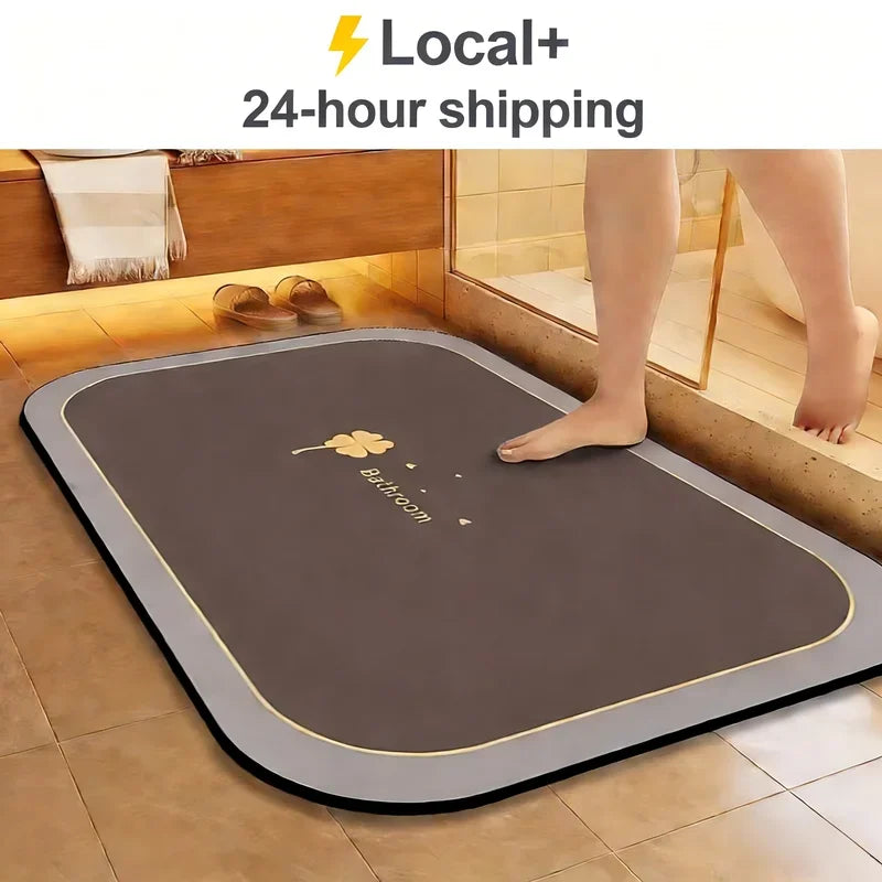 A brown diatomite bath mat with a gold trim is placed on a tiled bathroom floor.