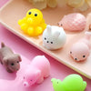 A collection of colorful, squishy animal stress relief toys including yellow, white, pink, and green figures on a light pink 