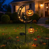 A solar garden stake light featuring a crescent moon and black cat silhouette with glowing orange pumpkins.