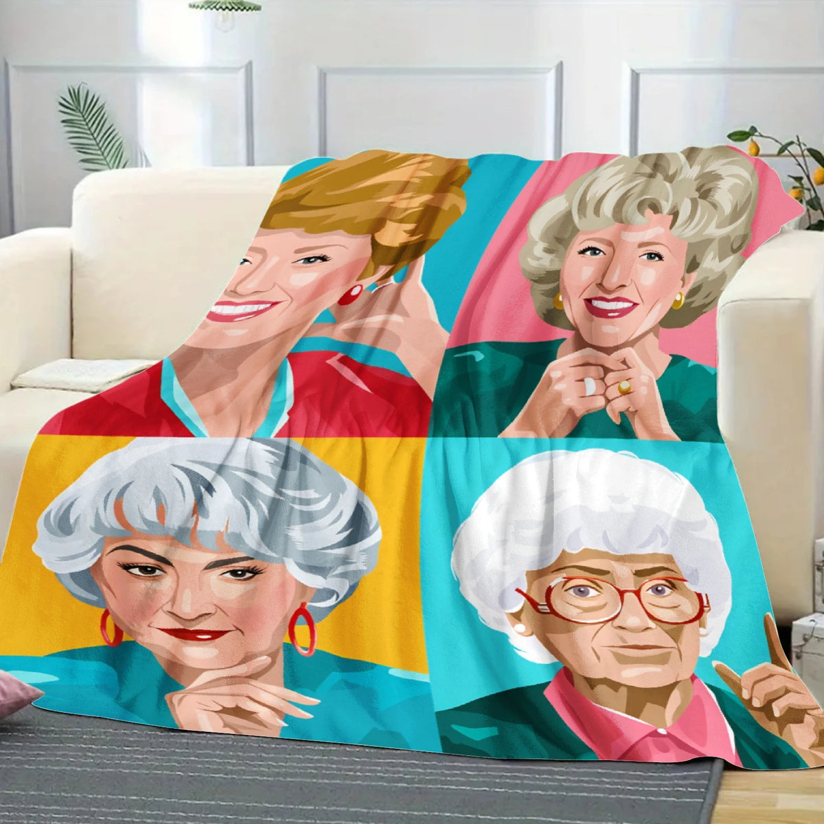 A colorful pop art blanket featuring portraits of the Golden Girls characters in various expressions.