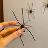 A hand holds a realistic black spider, which is a fridge magnet for funny prank decor.