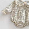 A light floral print cotton romper for a baby girl with delicate lace trim and ruffle details.