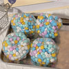 A collection of colorful squishy stress balls in various pastel shades are displayed on a tray.