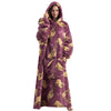 A woman wearing a purple oversized wearable blanket hoodie with a hood and sleeves.