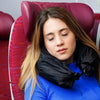 A young woman with long brown hair is resting her head on a red leather travel pillowcase organizer.