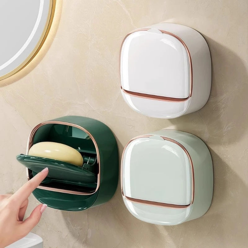 A wall-mounted soap holder with a lid and drainage in white and dark green colors.