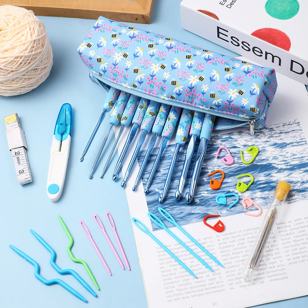 A collection of ergonomic crochet hooks in various sizes and colors with a blue bee design displayed on a sheet of paper.